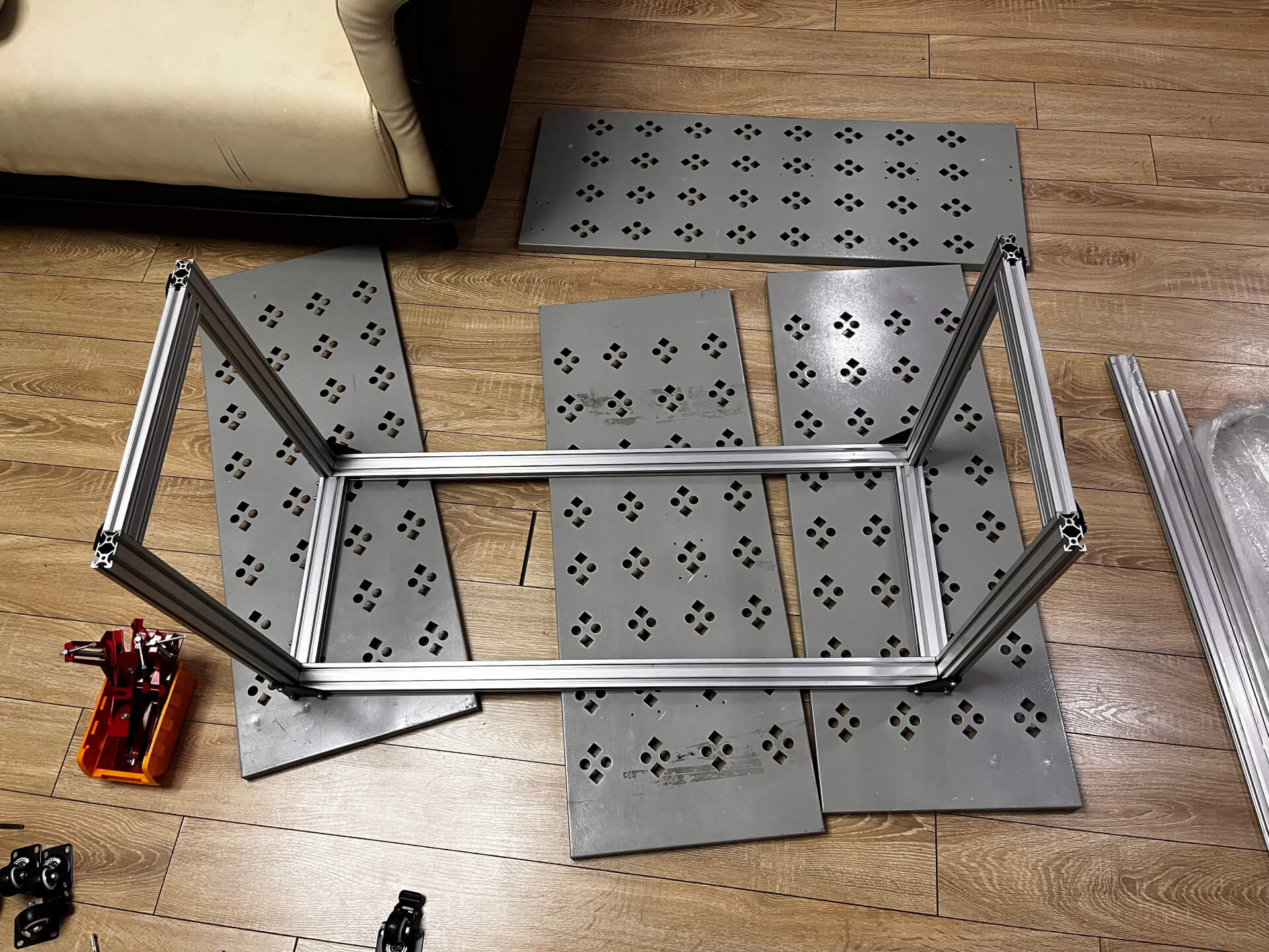 Partially assembled aluminum extrusion frame with perforated metal panels positioned for assembly