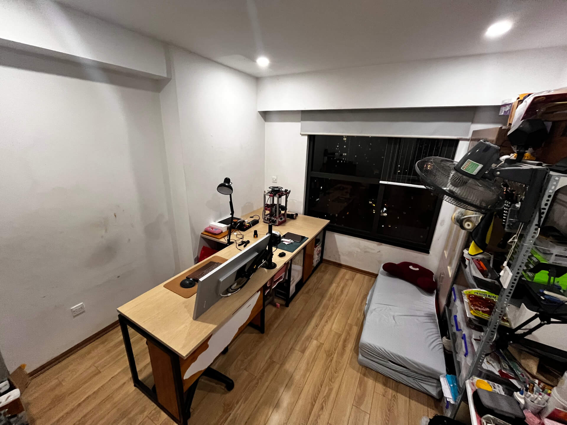 Wide angle view of renovated workshop showing three organized workstations with flat surfaces and improved storage solutions