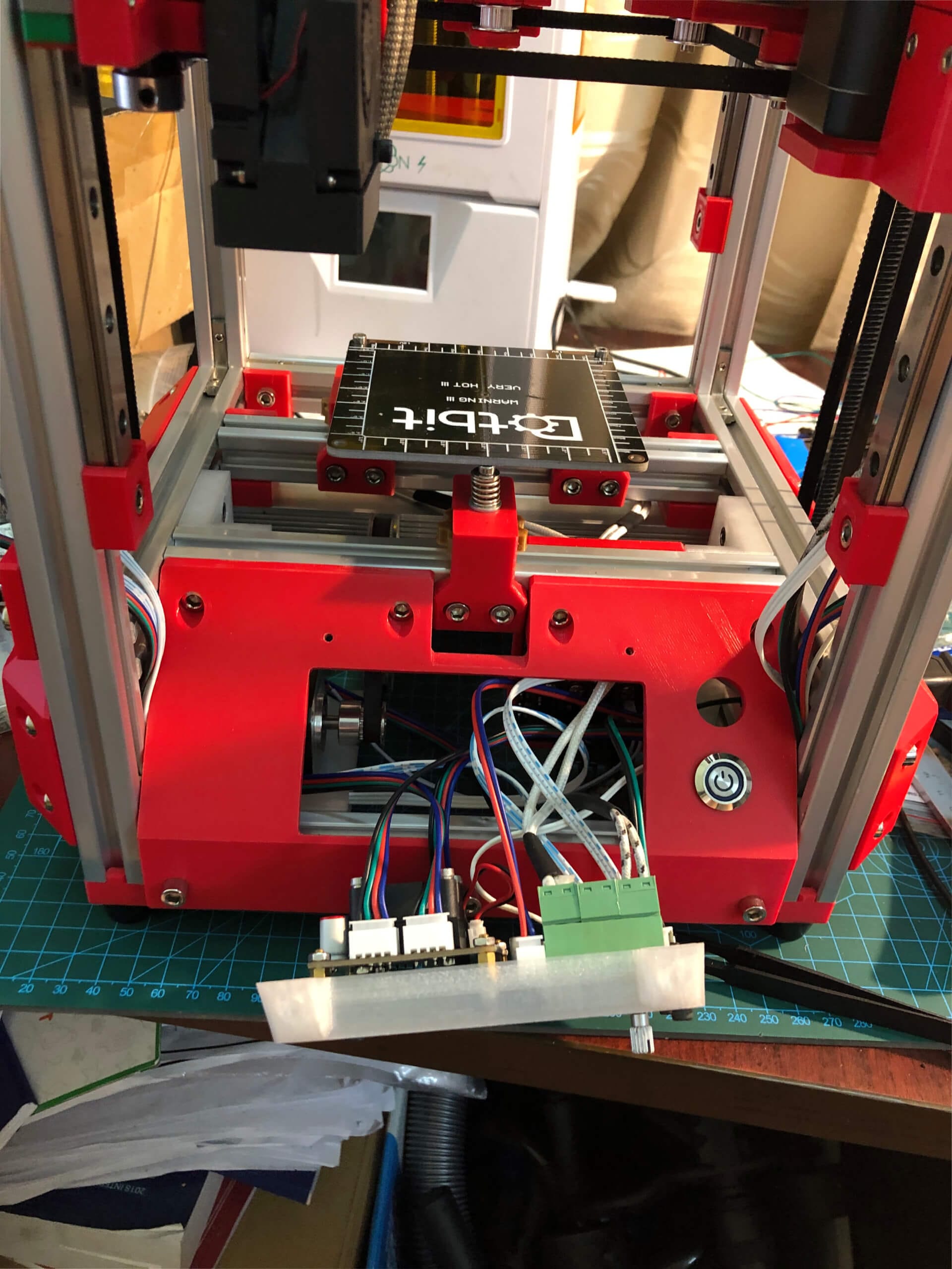 Compact all-in-one controller board and 100mm heated bed installed in Little Cube CoreXY 3D printer base with red printed frame
