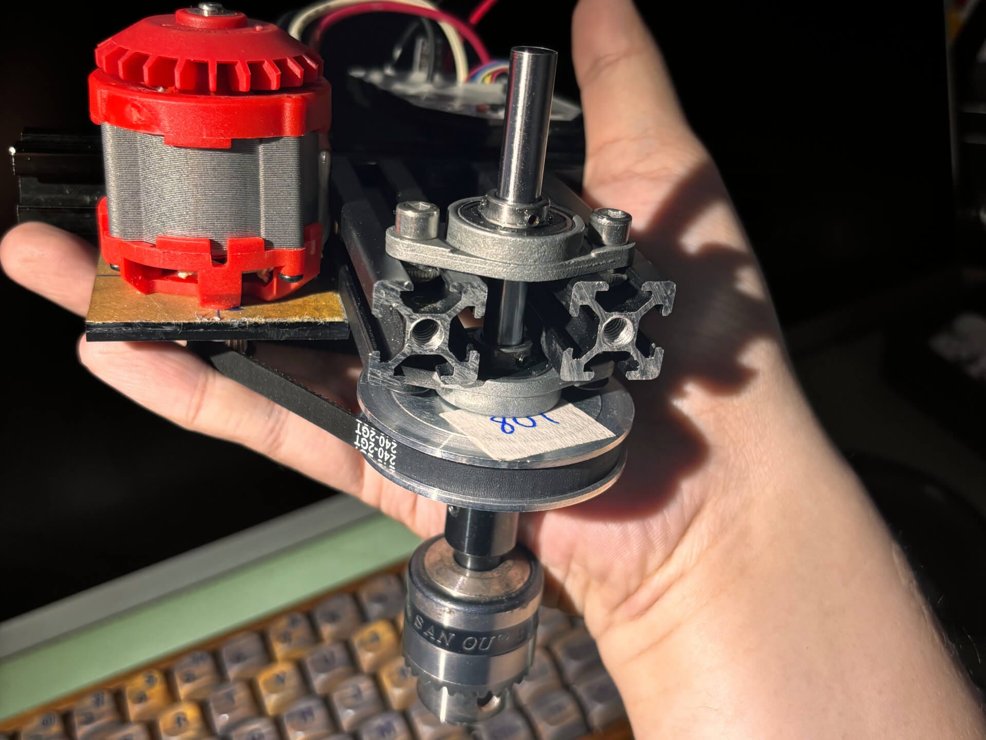 Hand holding the first version of the spindle assembly with acrylic motor mount and self-aligning pillow bearing
